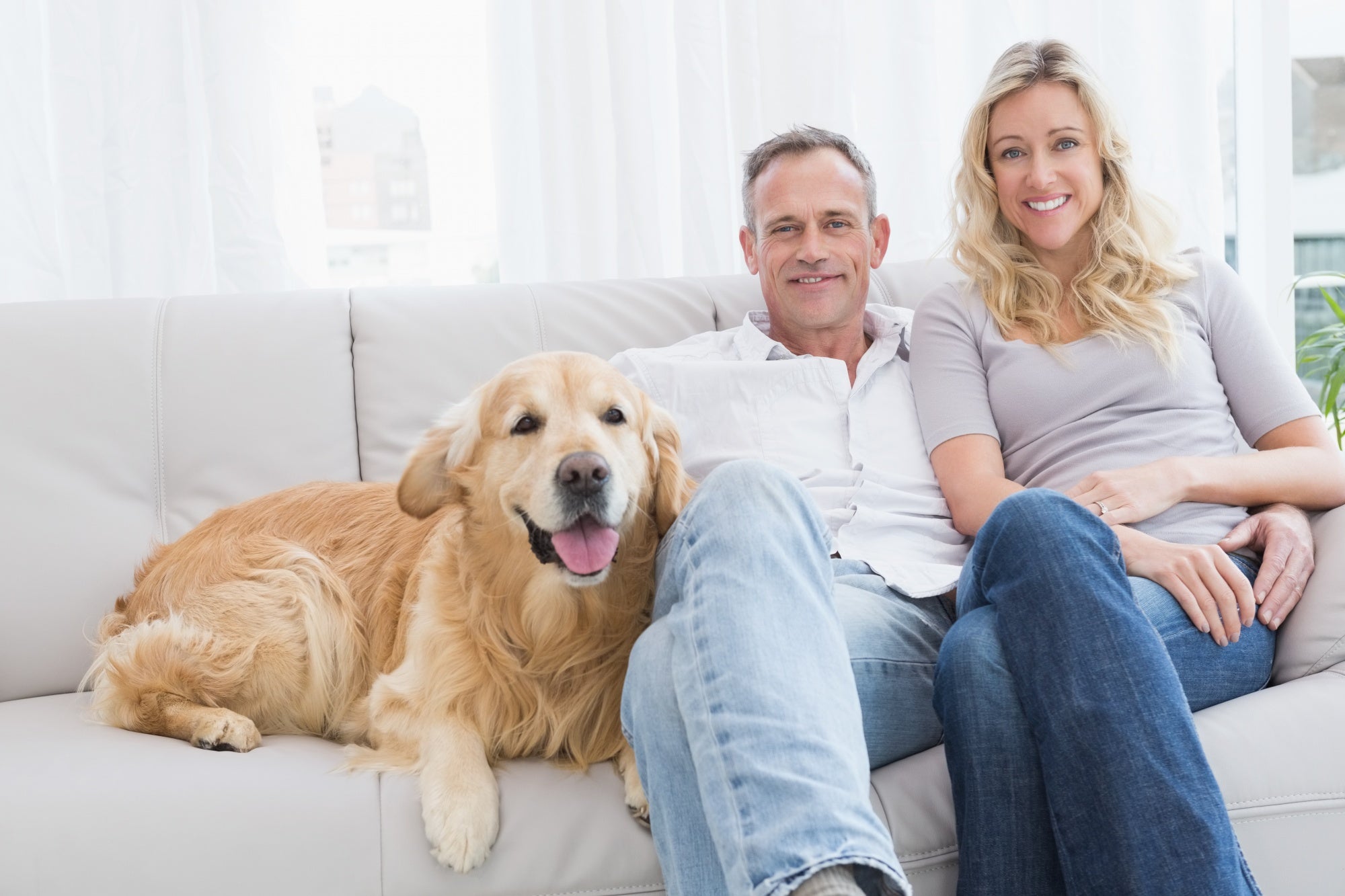 A couple relaxing with their dog on the sofa